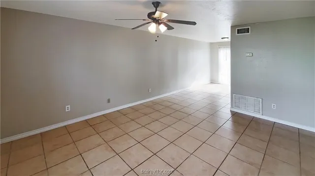 a view of an empty room and chandelier fan