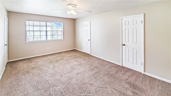 an empty room with windows and ceiling fan