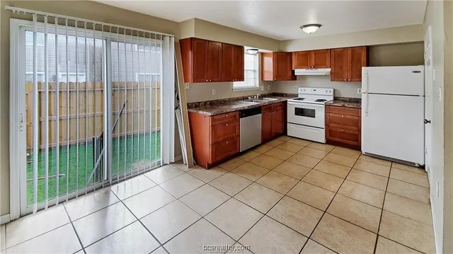 a kitchen with stainless steel appliances granite countertop a stove a refrigerator and a white cabinets