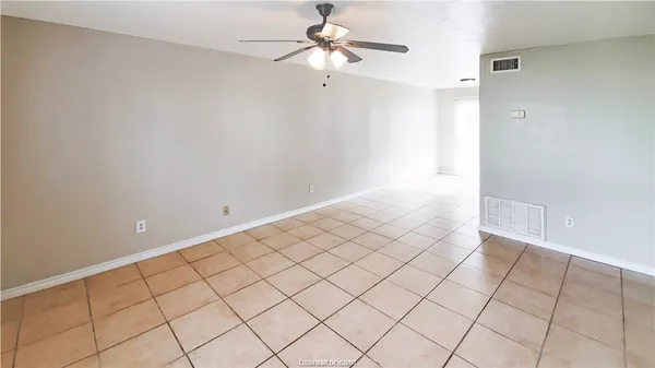 a view of an empty room and chandelier fan