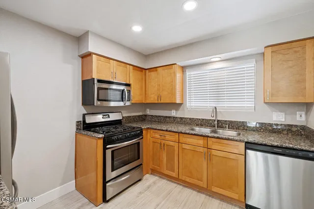 a kitchen with granite countertop cabinets stainless steel appliances a sink and a window