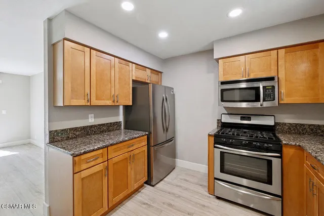 a kitchen with granite countertop cabinets stainless steel appliances and wooden floor