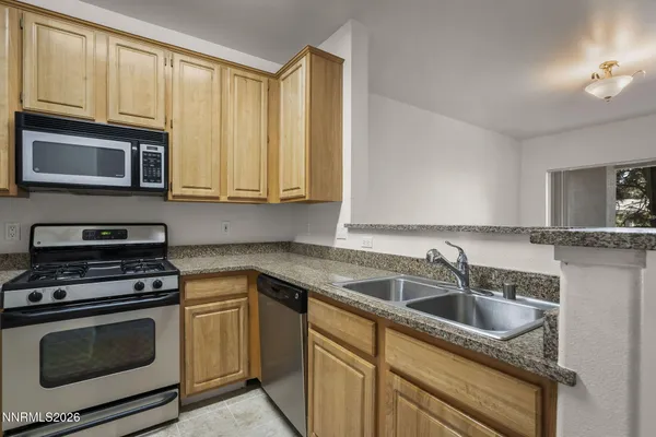 a kitchen with granite countertop cabinets stainless steel appliances a sink and dishwasher