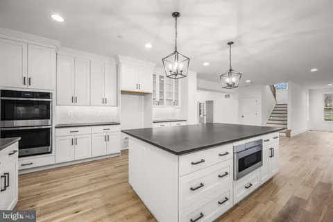 a kitchen with kitchen island granite countertop stainless steel appliances a stove cabinets and wooden floor