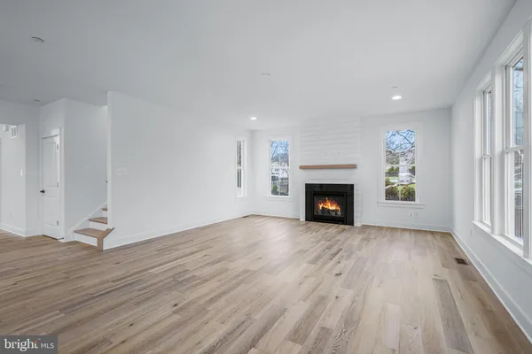 an empty room with wooden floor fireplace and windows