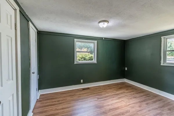 a view of hallway with window and wooden floor