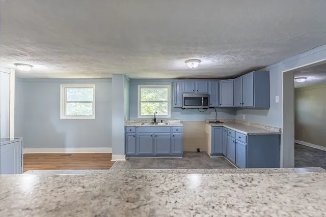 a kitchen with a refrigerator sink cabinets and wooden floor
