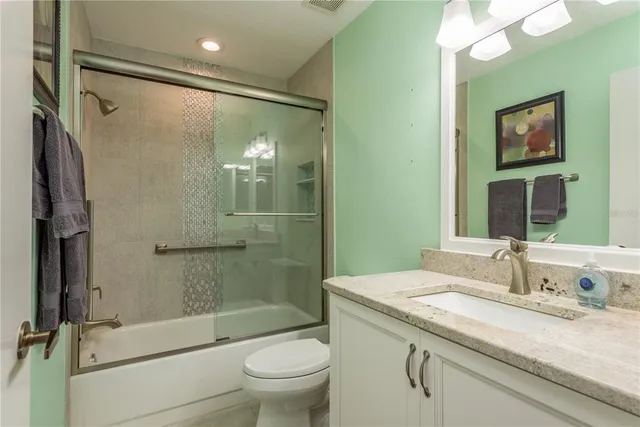 a bathroom with a granite countertop sink toilet and shower