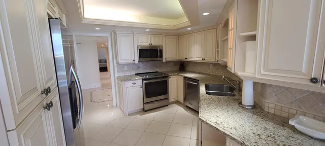 a kitchen with stainless steel appliances granite countertop a stove a sink and a refrigerator