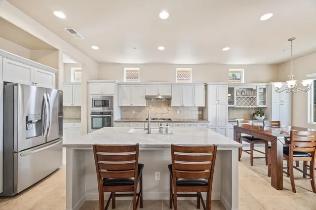 a kitchen with stainless steel appliances a refrigerator a stove a sink and chairs
