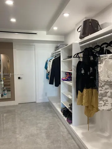 a view of walk in closet with clothes and shoes