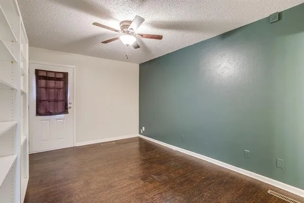 an empty room with a chandelier fan and windows