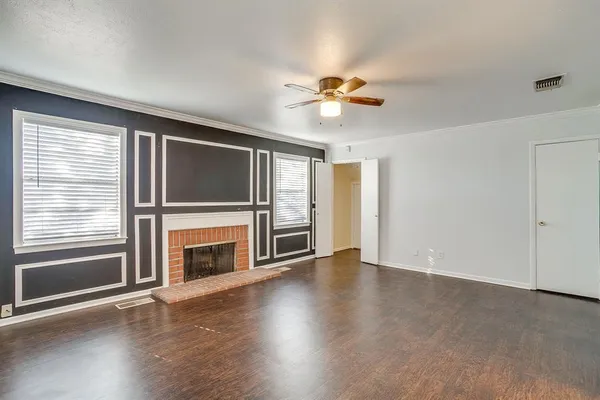 an empty room with wooden floor fireplace and windows