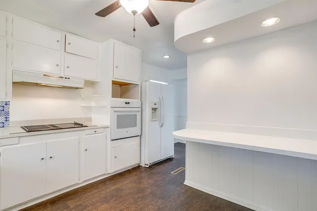 a kitchen with stainless steel appliances a refrigerator and white cabinets
