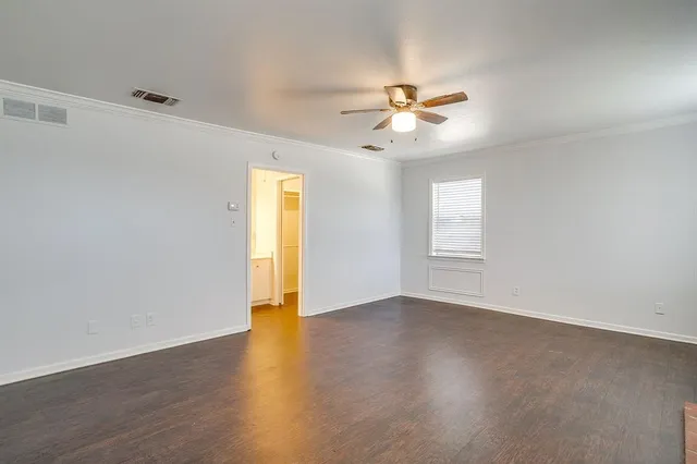 a view of an empty room with window and wooden floor