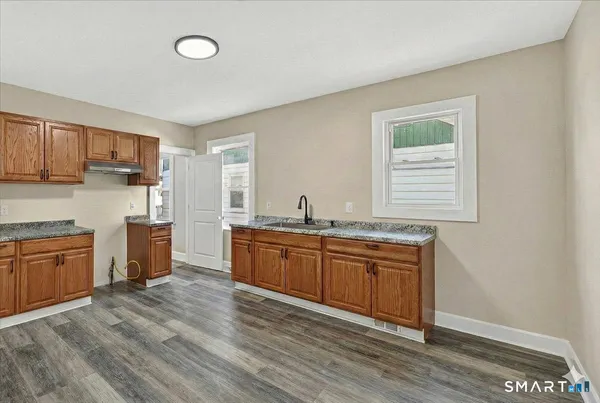 a kitchen with stainless steel appliances granite countertop a sink cabinets and wooden floor