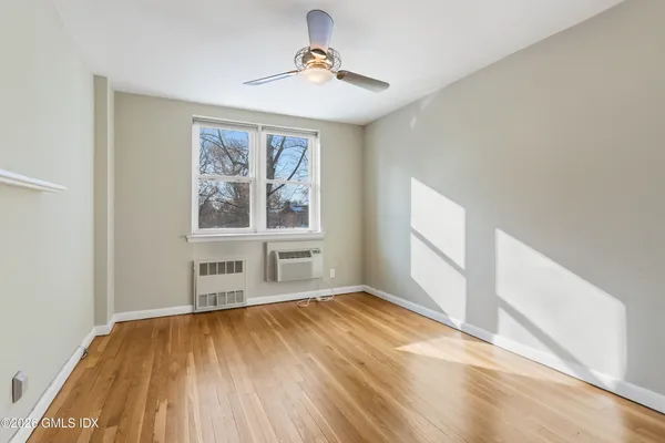 a view of empty room with wooden floor and fan