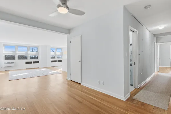 a view of a hallway with wooden floor and chandelier