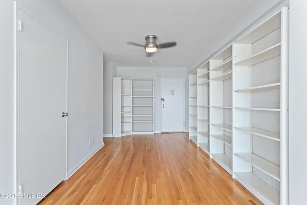 a view of empty room with wooden floor and fan