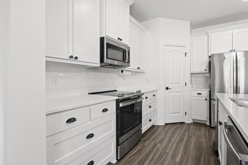 103 St James Mount Mount Pleasant, TX 75455 - Photo 16 of 39 a kitchen with stainless steel appliances white cabinets and a stove a refrigerator with wooden floor