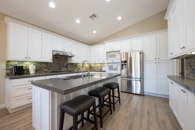 a kitchen with stainless steel appliances granite countertop a white cabinets and wooden floor