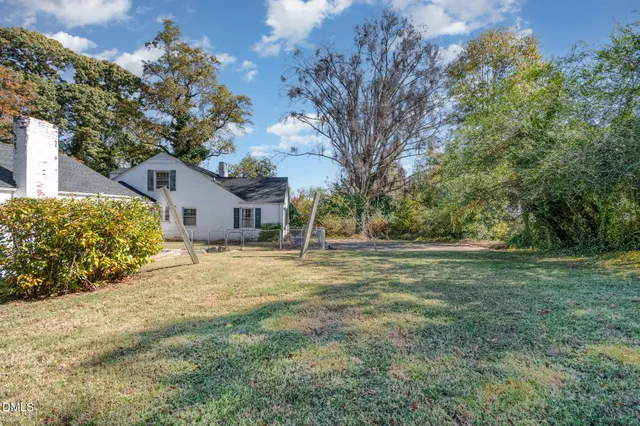 a white house with a big yard and large trees