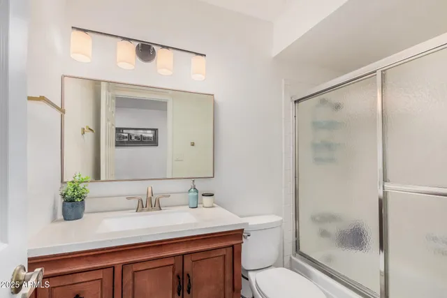 a bathroom with a granite countertop sink a toilet a mirror and shower