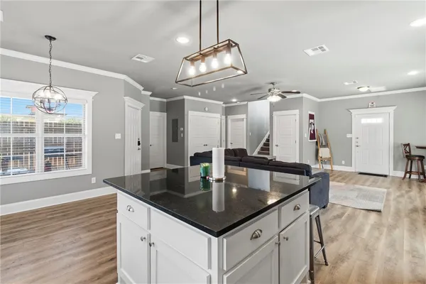 a kitchen with kitchen island granite countertop a sink a counter top space and living room view