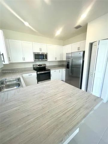 a kitchen with granite countertop a refrigerator stove and sink