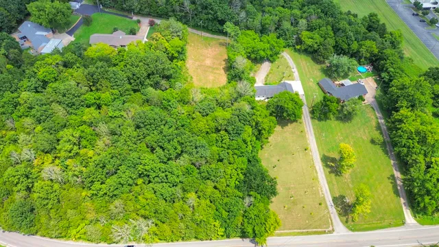 an aerial view of residential house with outdoor space and trees all around