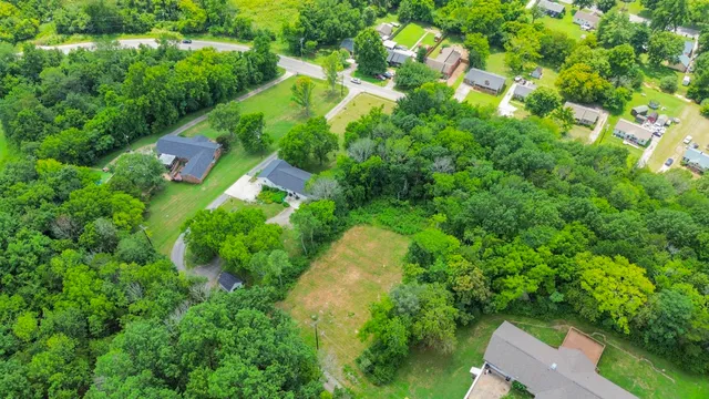 an aerial view of residential house with outdoor space and trees all around