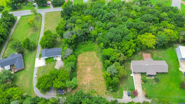 an aerial view of a house with a yard and large trees all around