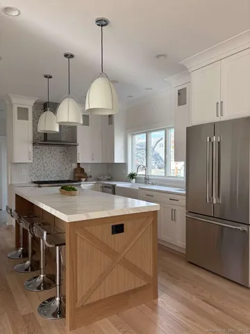 a kitchen with stainless steel appliances granite countertop a sink a stove a refrigerator and island