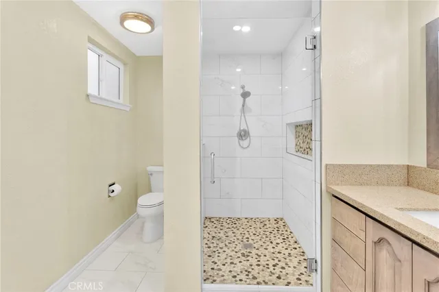 a bathroom with a granite countertop sink a toilet and shower