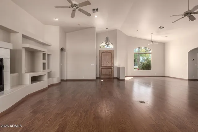 an empty room with wooden floor and a kitchen
