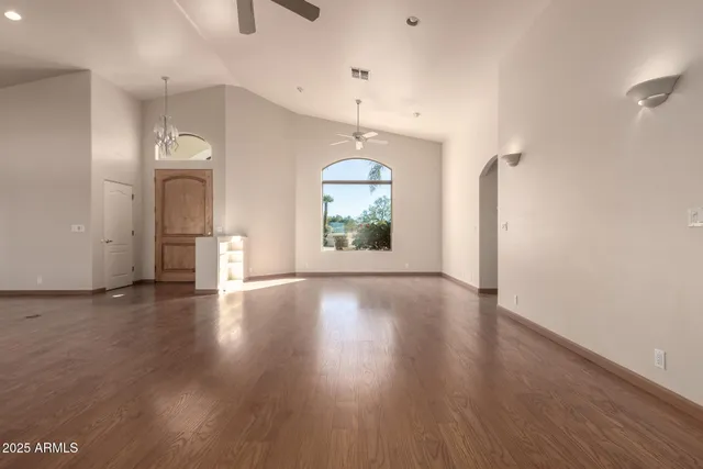 an empty room with wooden floor cabinet and windows