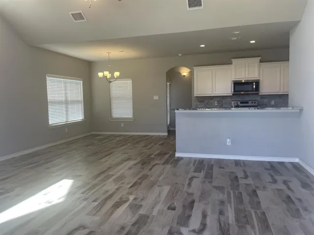 a view of kitchen and empty room with wooden floor