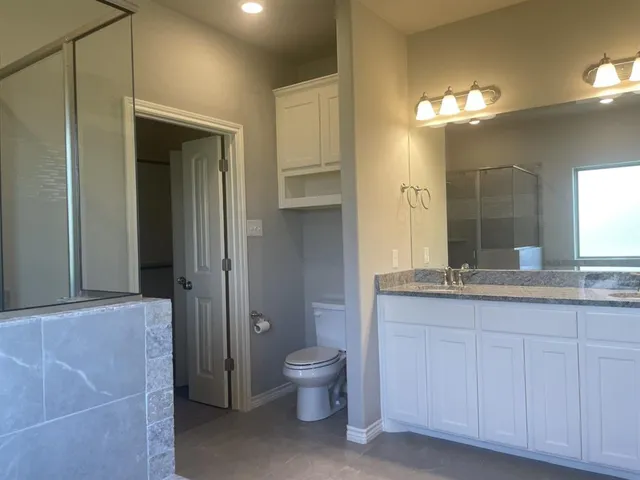 a bathroom with a granite countertop sink a toilet and a large mirror
