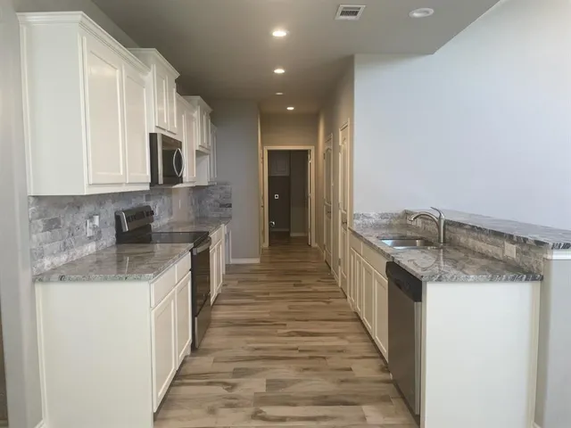 a large kitchen with stainless steel appliances granite countertop a lot of counter space and wooden floor