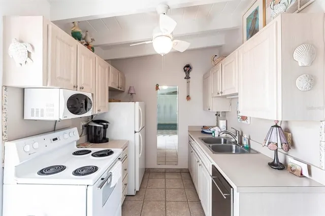 a kitchen with stainless steel appliances a sink a stove a refrigerator and white cabinets