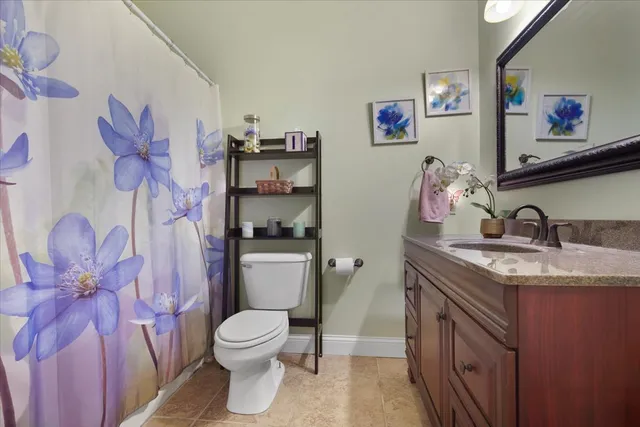 a bathroom with a granite countertop sink a toilet and a shower curtain