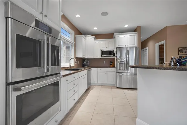 a large kitchen with stainless steel appliances kitchen island granite countertop a refrigerator and a stove top oven