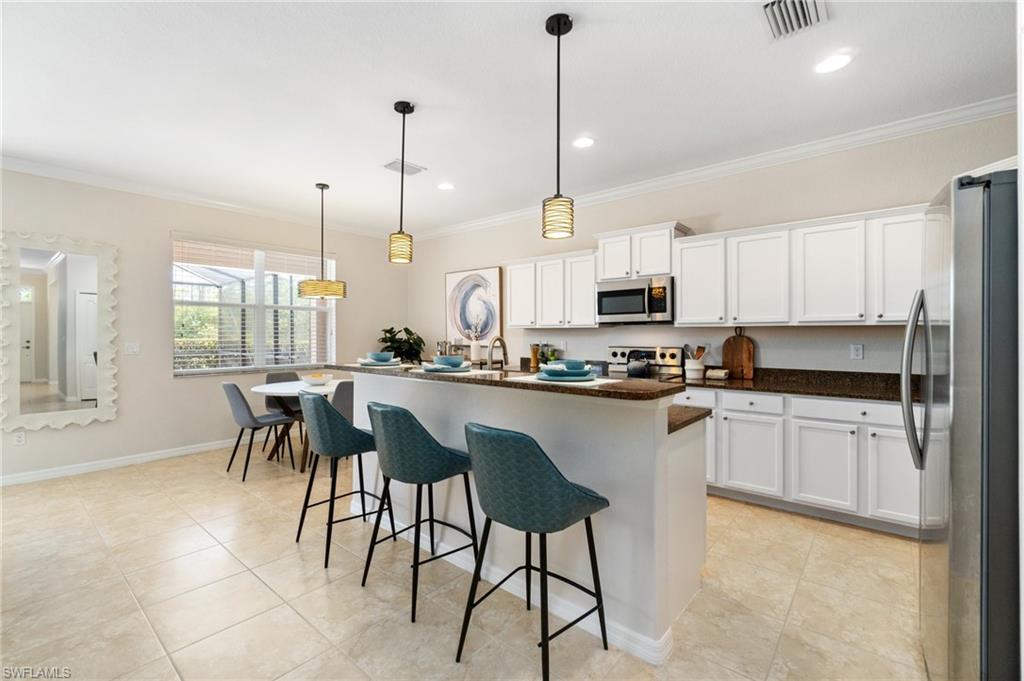 21017 Bella Terra Boulevard Estero, FL 33928 - Photo 9 of 45 a kitchen with stainless steel appliances granite countertop a stove a sink a microwave a dining table chairs and view living room