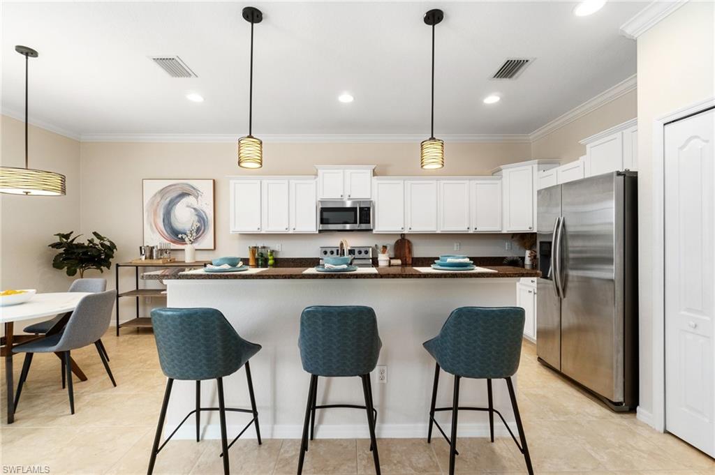 21017 Bella Terra Boulevard Estero, FL 33928 - Photo 10 of 45 a kitchen with stainless steel appliances granite countertop a sink a stove a refrigerator and island with wooden floor