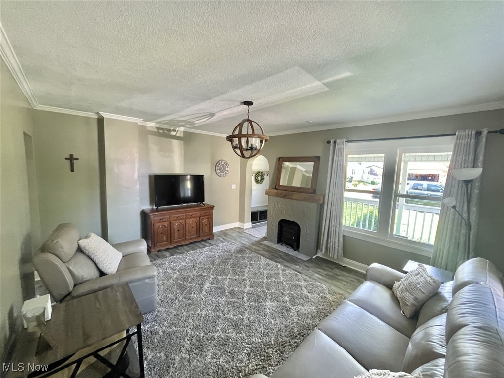4440 Dryden Court Southwest Canton, OH 44708 - Photo 8 of 28 Living area featuring ornamental molding, a textured ceiling, wood finished floors, a fireplace with flush hearth, and a chandelier