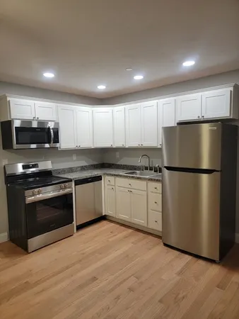 a kitchen with granite countertop a refrigerator stove top oven and cabinets