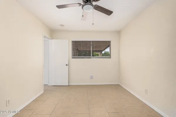 an empty room with a ceiling fan and window