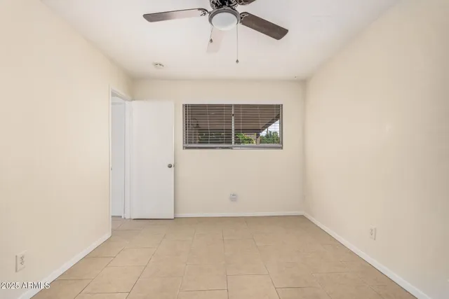an empty room with a ceiling fan and window