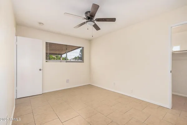 an empty room with a window and a ceiling fan