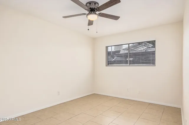 an empty room with a ceiling fan and window